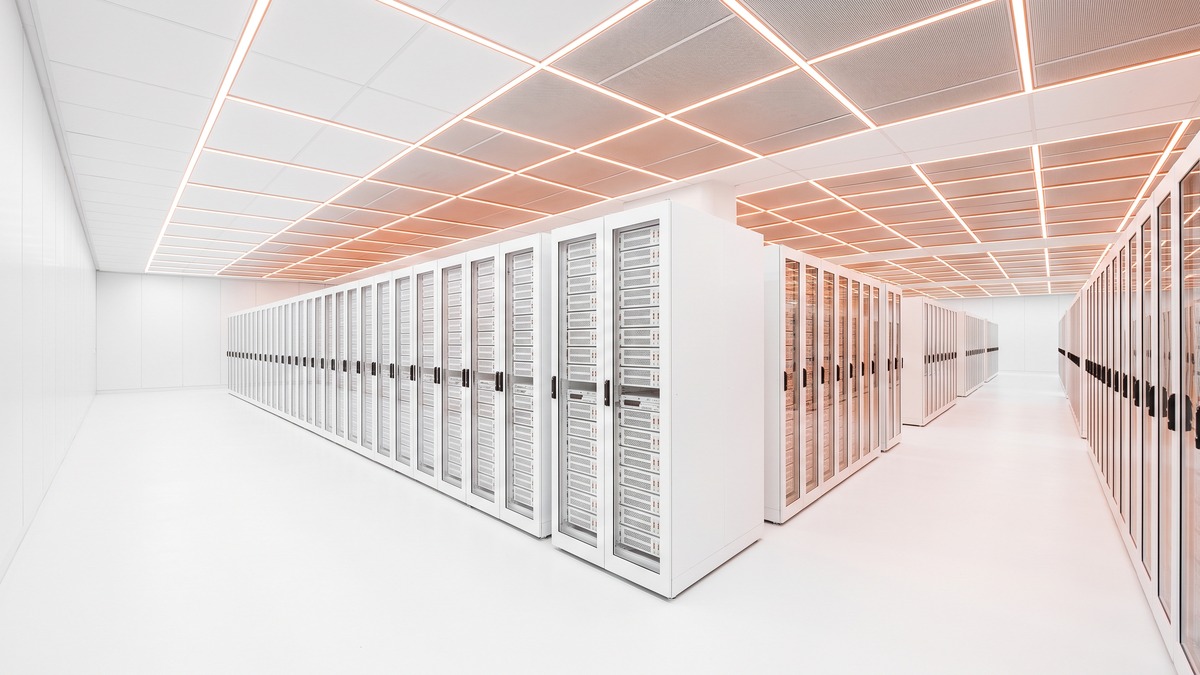 Wide view of a bright hyperscale data center hall with long rows of server racks